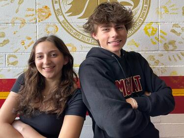 Two students, arms crossed and leaning into eachother