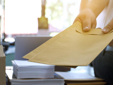 Office clerk or secretary handing over documents and brown envelopes